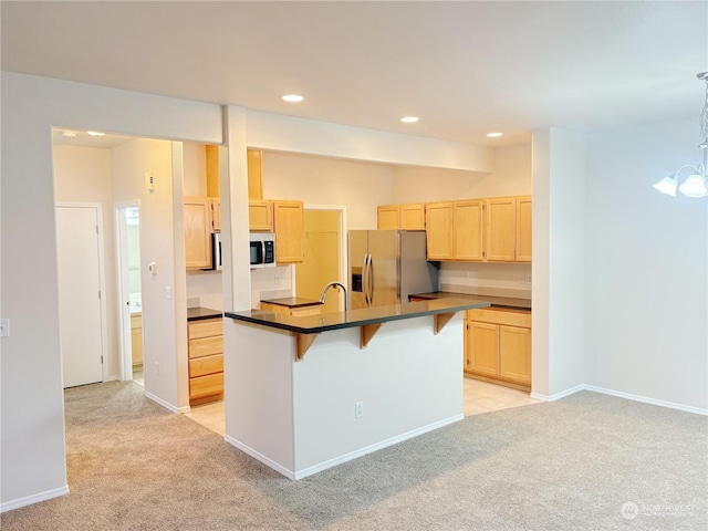 kitchen with stainless steel appliances, a kitchen bar, a kitchen island with sink, and light carpet