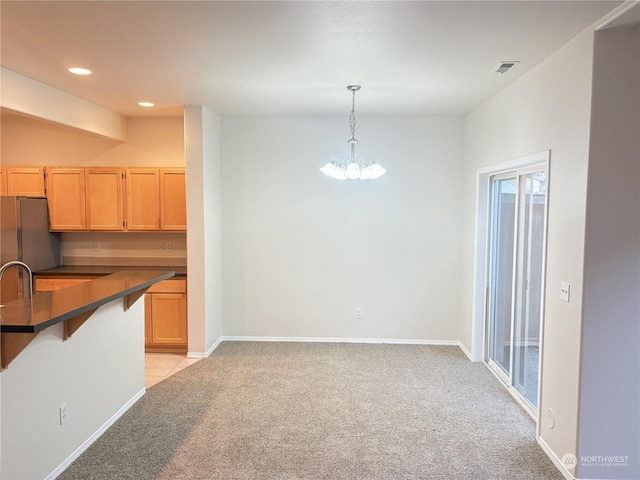 kitchen featuring hanging light fixtures, a breakfast bar area, light colored carpet, and light brown cabinetry