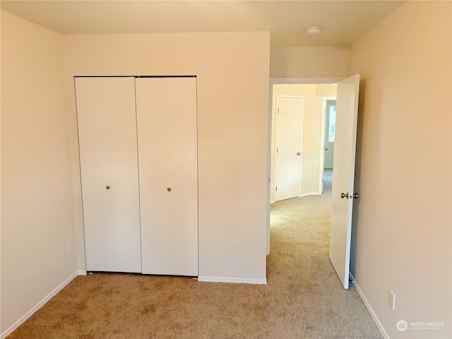 unfurnished bedroom featuring light colored carpet and a closet