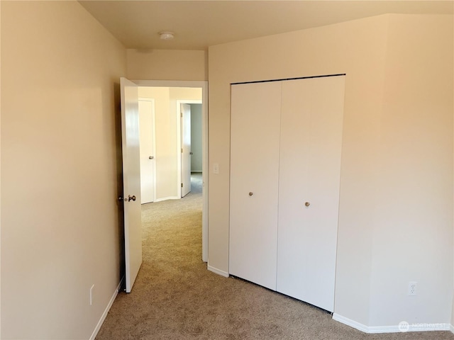 unfurnished bedroom featuring light colored carpet and a closet