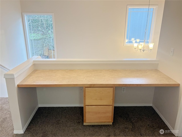 unfurnished office featuring built in desk, dark carpet, and a notable chandelier