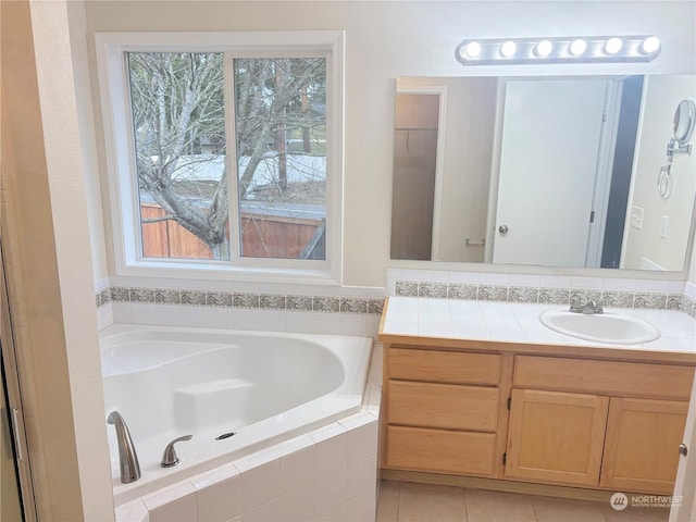 bathroom featuring tile patterned floors, tiled bath, and vanity