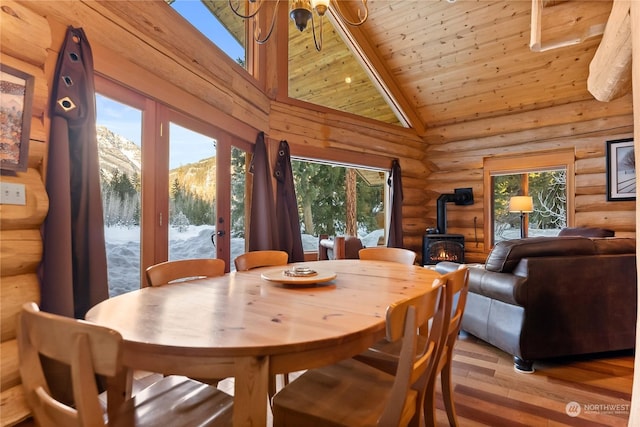 dining area featuring a wealth of natural light, a mountain view, high vaulted ceiling, and a wood stove