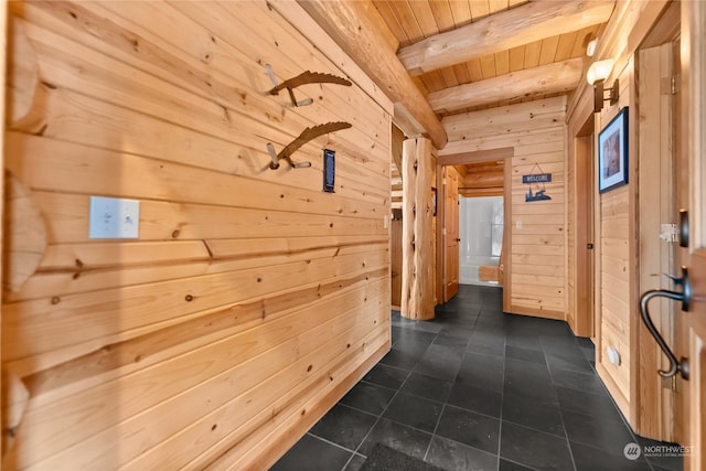 hallway featuring beamed ceiling, wood ceiling, wooden walls, and dark tile patterned flooring