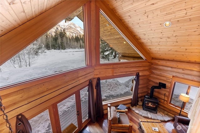 room details with hardwood / wood-style floors, wood ceiling, rustic walls, and a wood stove