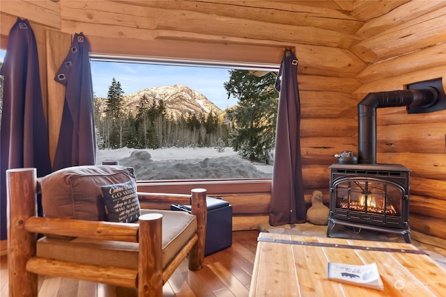 sitting room with rustic walls, a mountain view, hardwood / wood-style floors, and a wood stove