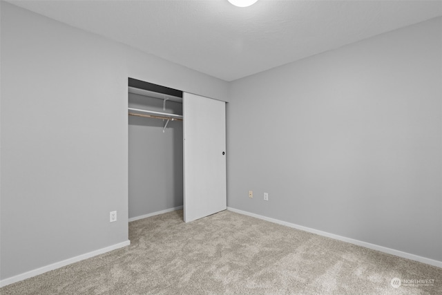 unfurnished bedroom featuring light carpet and a closet