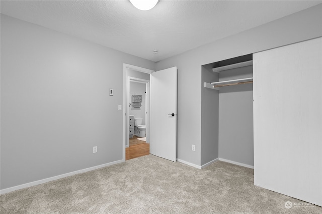 unfurnished bedroom with light colored carpet, a textured ceiling, and a closet