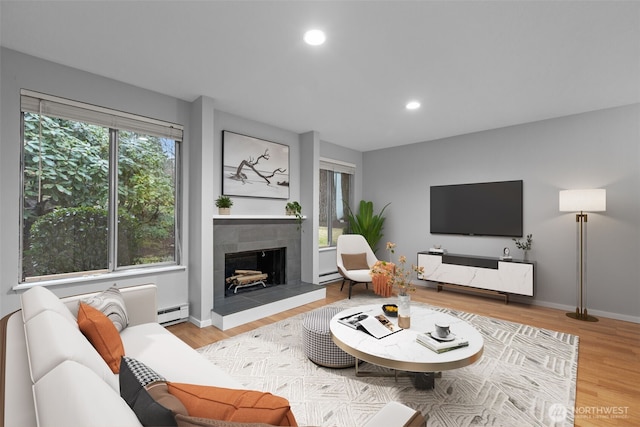 living area with baseboards, light wood-style flooring, recessed lighting, a tiled fireplace, and baseboard heating