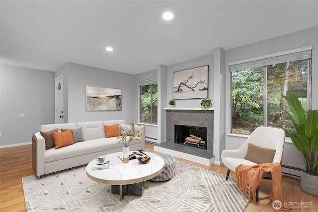 living area featuring baseboards, recessed lighting, light wood-style flooring, a fireplace, and a baseboard radiator