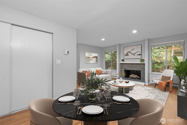 dining area featuring recessed lighting, a baseboard heating unit, a tile fireplace, and light wood finished floors