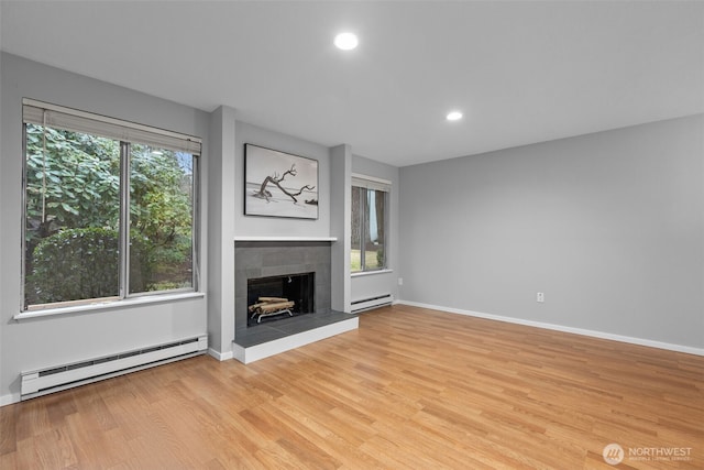 unfurnished living room with recessed lighting, a baseboard radiator, light wood-style flooring, and a tiled fireplace