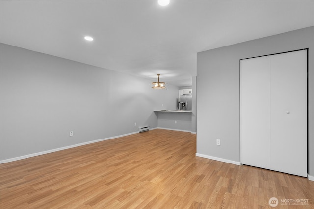 unfurnished living room with baseboard heating, recessed lighting, baseboards, and light wood-style floors