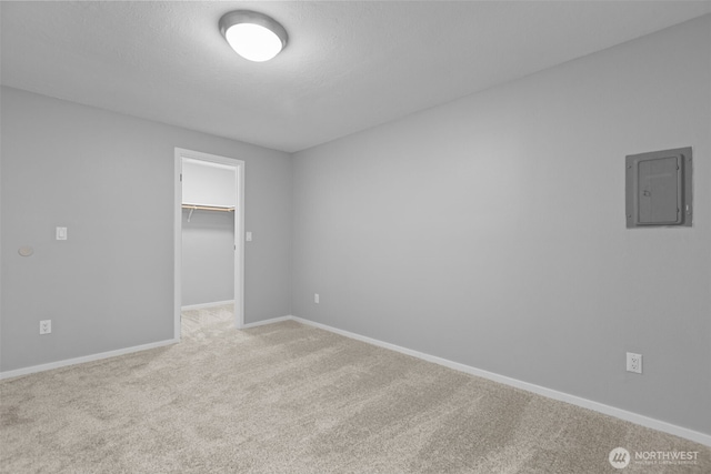 unfurnished bedroom featuring a walk in closet, electric panel, a closet, carpet flooring, and baseboards