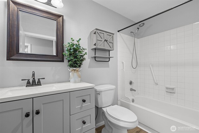 full bath featuring washtub / shower combination, toilet, wood finished floors, and vanity