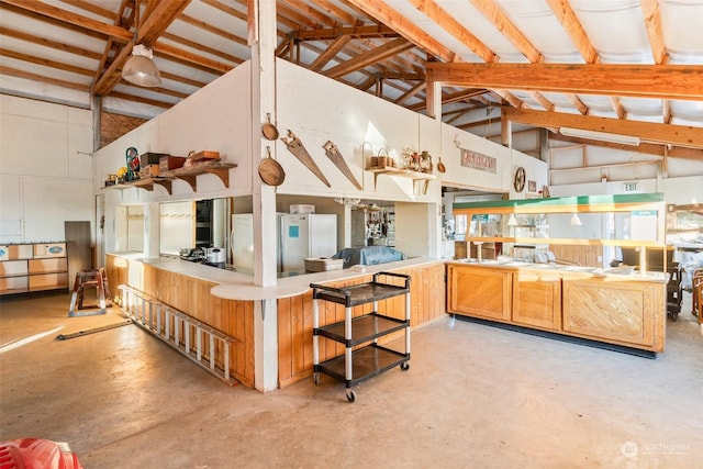 kitchen with high vaulted ceiling, stainless steel refrigerator, beam ceiling, and kitchen peninsula