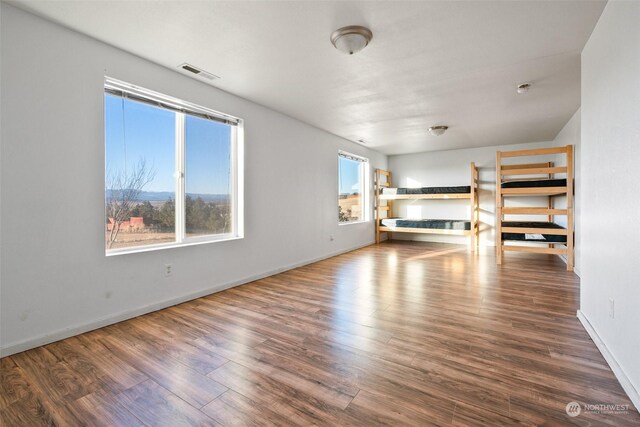 unfurnished living room featuring plenty of natural light and dark hardwood / wood-style floors