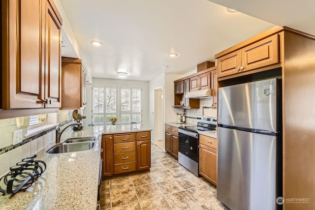 kitchen with light stone counters, sink, tasteful backsplash, and appliances with stainless steel finishes