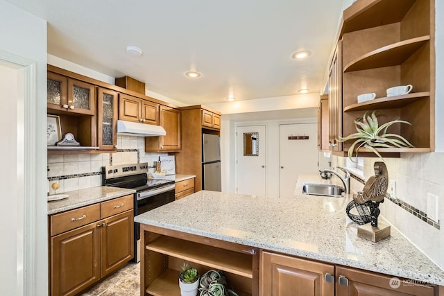 kitchen with appliances with stainless steel finishes, sink, backsplash, and light stone counters