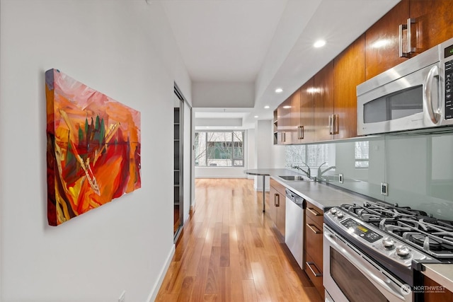 kitchen with sink, decorative backsplash, light hardwood / wood-style flooring, and stainless steel appliances