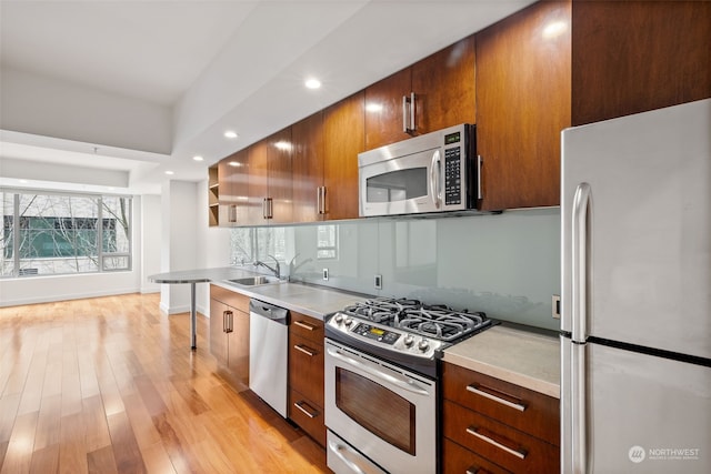 kitchen with appliances with stainless steel finishes, sink, and light wood-type flooring