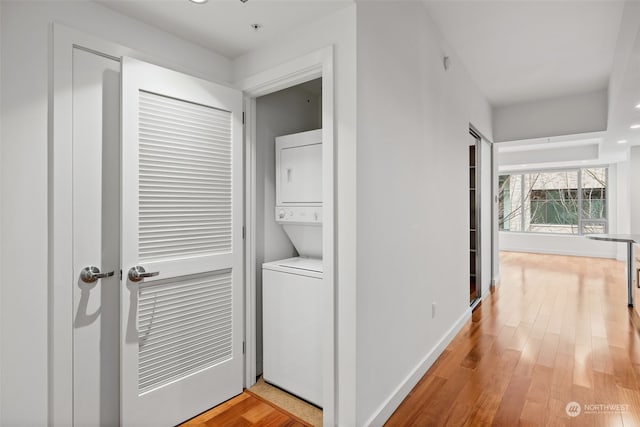 washroom with light hardwood / wood-style floors and stacked washer and clothes dryer