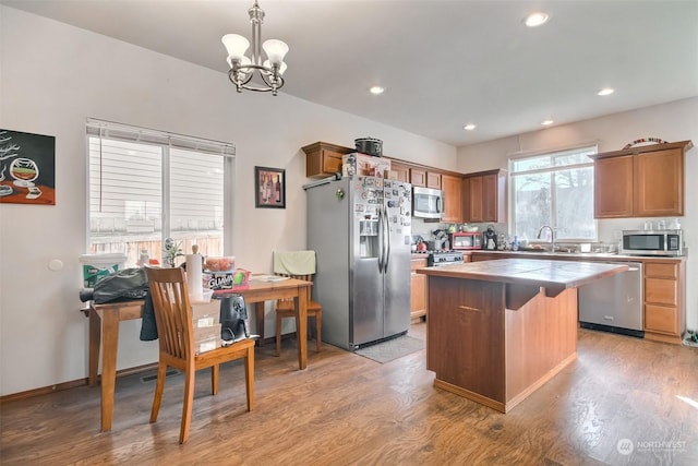 kitchen featuring hanging light fixtures, a kitchen island, stainless steel appliances, and light wood-type flooring