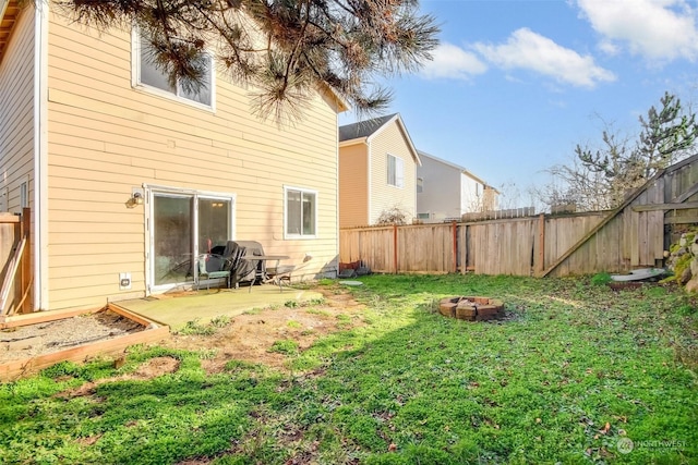 rear view of property featuring a yard, a patio, and an outdoor fire pit