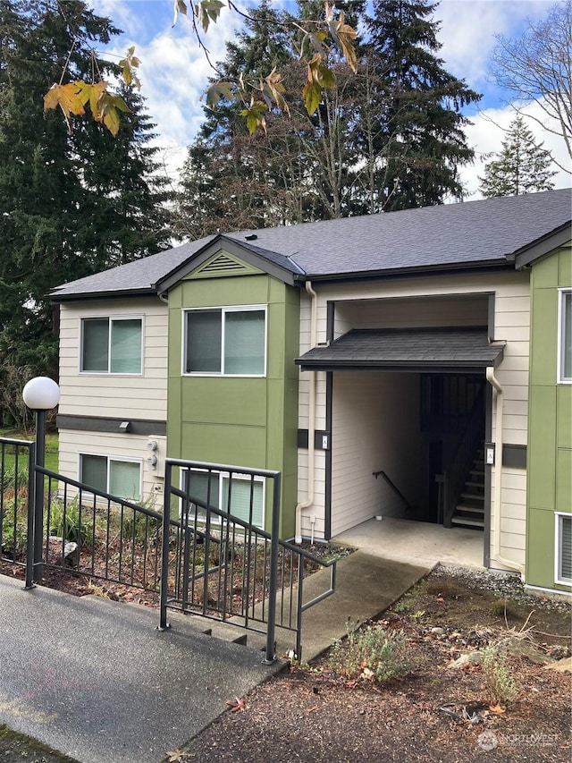 view of front of home with stairs and a shingled roof