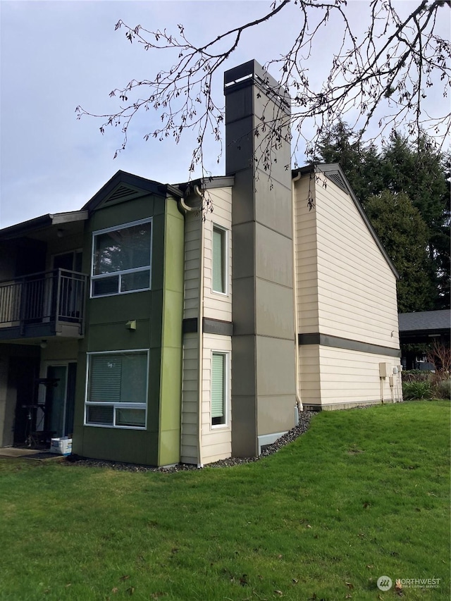 view of side of home featuring a chimney and a lawn