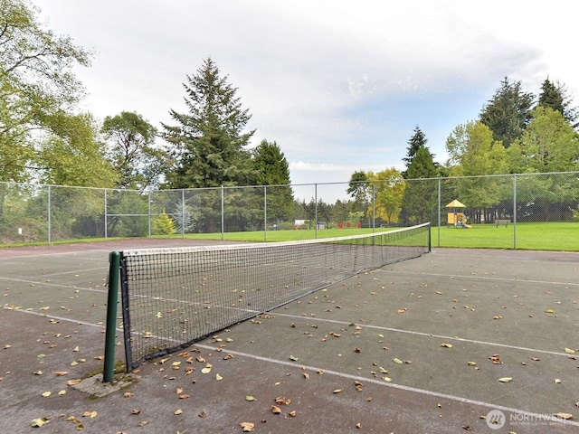 view of community with a tennis court, playground community, and fence