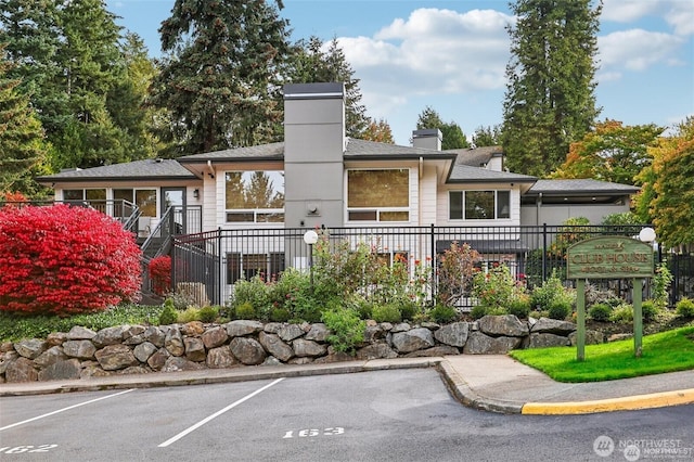 rear view of property featuring uncovered parking, a chimney, and fence