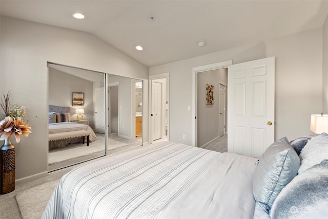 bedroom with vaulted ceiling, connected bathroom, light carpet, and a closet