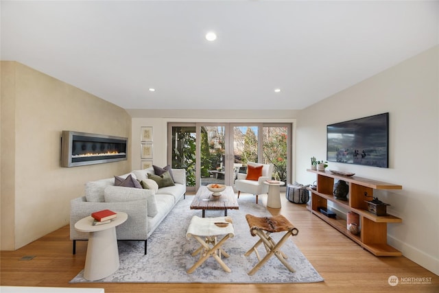 living room with light hardwood / wood-style flooring, french doors, and vaulted ceiling