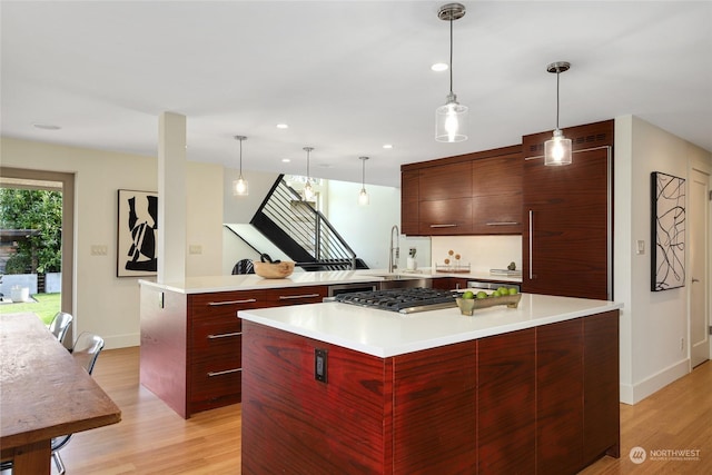 kitchen with a large island, hanging light fixtures, stainless steel gas cooktop, and light wood-type flooring