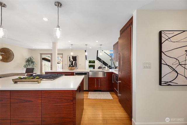 kitchen with pendant lighting, light hardwood / wood-style flooring, stainless steel appliances, and kitchen peninsula