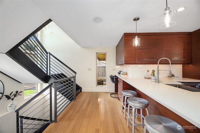 kitchen featuring sink, light hardwood / wood-style flooring, a breakfast bar area, and hanging light fixtures