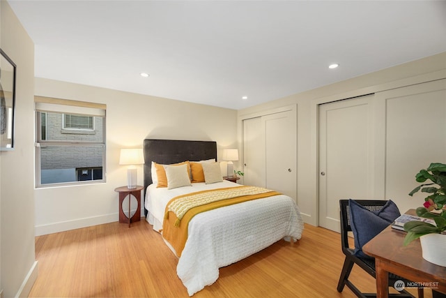 bedroom featuring multiple closets and light hardwood / wood-style floors