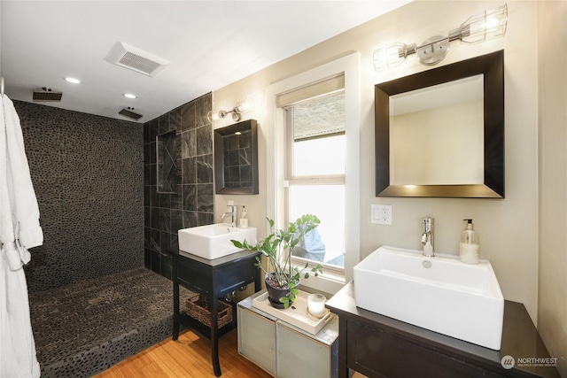 bathroom featuring hardwood / wood-style flooring, vanity, and a tile shower