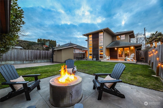 rear view of property with a shed, a wooden deck, a patio, and an outdoor fire pit