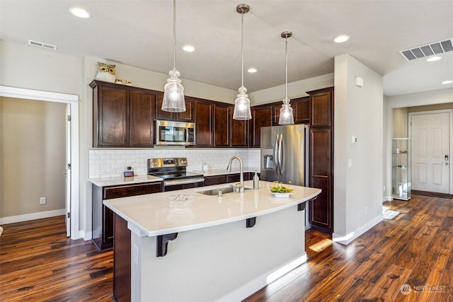 kitchen with sink, stainless steel appliances, a kitchen breakfast bar, a center island with sink, and decorative light fixtures