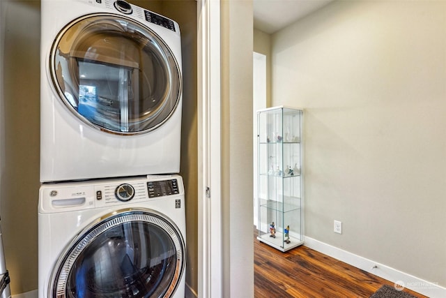 clothes washing area with stacked washer / drying machine and dark wood-type flooring