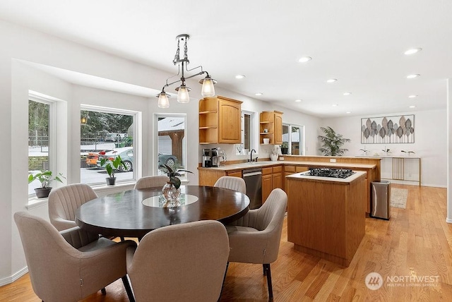 kitchen featuring decorative light fixtures, dishwasher, sink, light hardwood / wood-style floors, and black gas stovetop