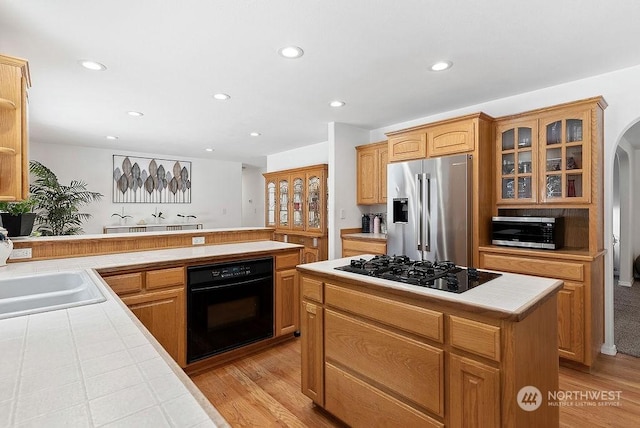 kitchen with a kitchen island, tile countertops, black appliances, sink, and kitchen peninsula