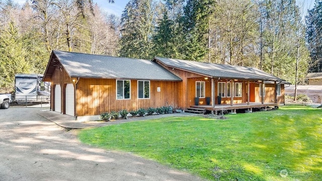 rear view of house with a porch, a garage, and a lawn