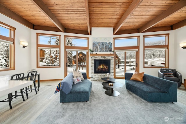 living room featuring beam ceiling, a stone fireplace, wood ceiling, and hardwood / wood-style floors