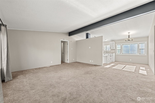 unfurnished living room featuring light colored carpet, lofted ceiling with beams, a chandelier, and a textured ceiling