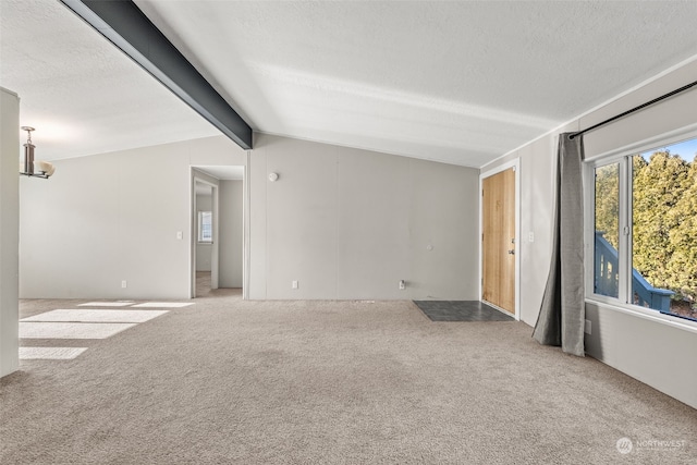 empty room featuring lofted ceiling with beams, light carpet, and a textured ceiling