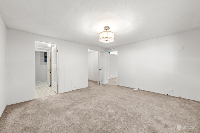 spare room featuring light carpet and a textured ceiling