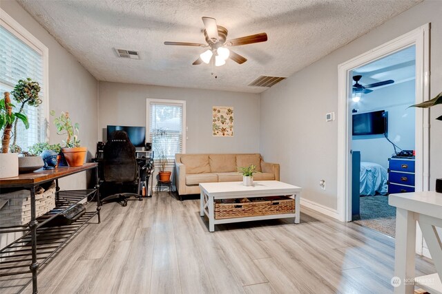 office area with a textured ceiling, light hardwood / wood-style floors, and ceiling fan